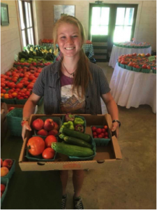 Emma Counce, Recycling Coordinator Intern, carrying a basket of produce at her internship with Native Son Farms.